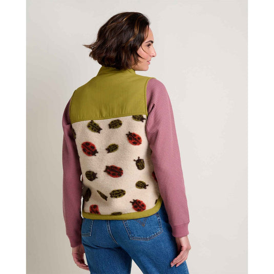 Person wearing a colorful vest with ladybug pattern on a plain background
