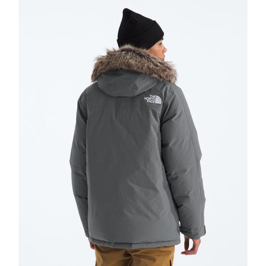 Person wearing a gray winter coat with fur hood and The North Face logo on a white background