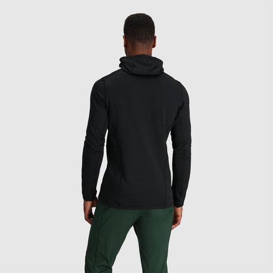 Person wearing a black jacket and green pants on a light gray background
