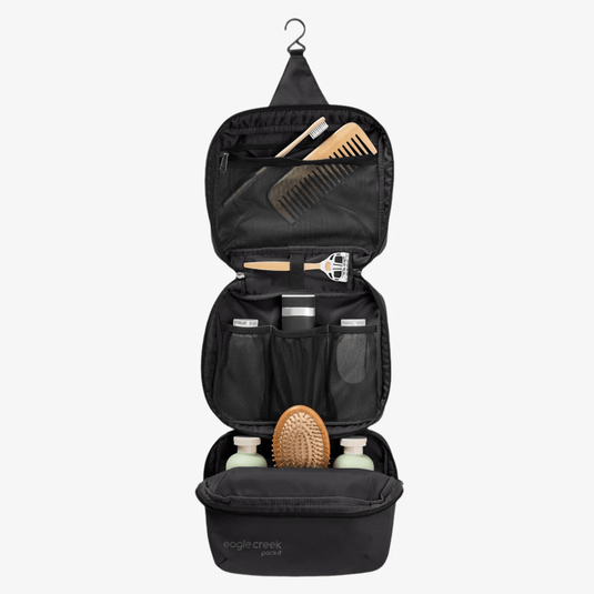 Black hanging toiletry bag with grooming products on a white background