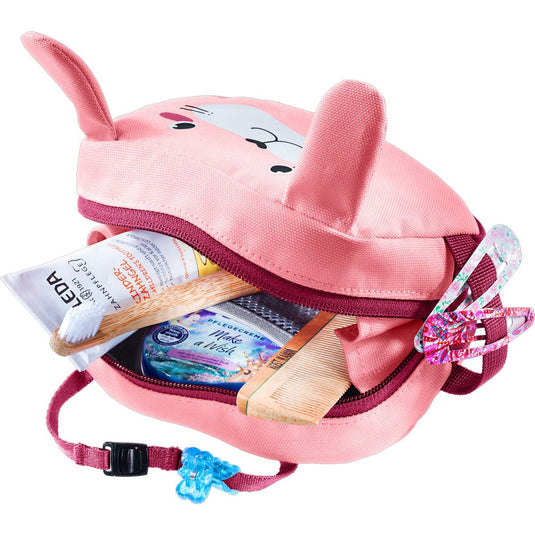 Pink children's backpack with animal ears filled with toiletries on a white background