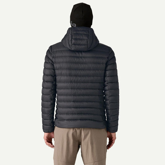 Person wearing a dark gray puffer jacket and beige pants on a white background