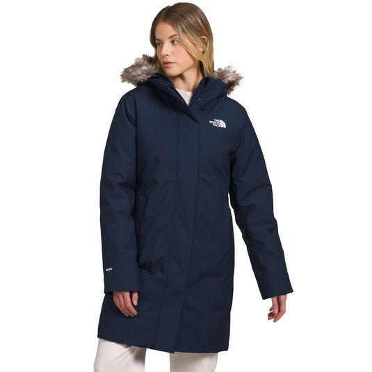 Woman wearing a navy blue coat with fur-lined hood on a white background