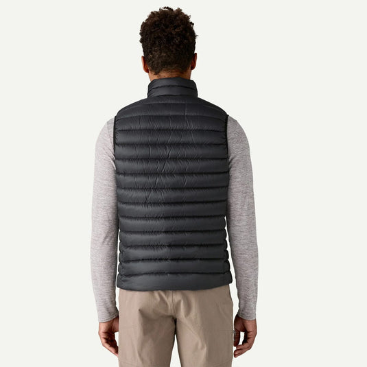 Person wearing a gray puffer vest over a light gray long-sleeve shirt on a white background