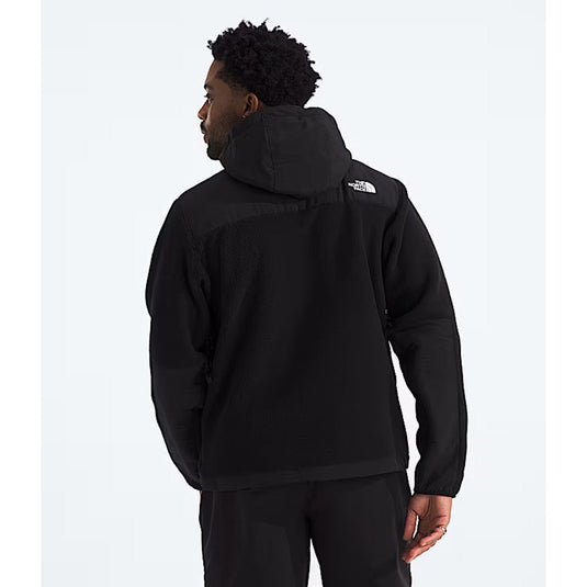 Person wearing a black hoodie with a brand logo on the back against a white background