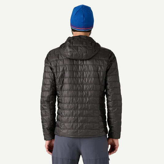 Person wearing a gray quilted jacket and blue beanie on a white background