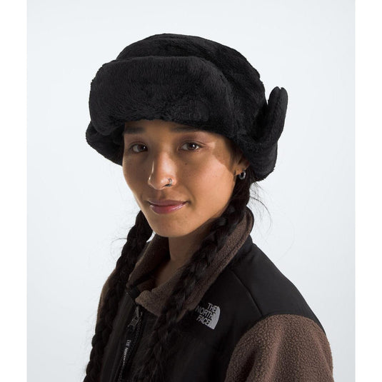 Person wearing a black fur-trimmed hat and brown scarf on a white background