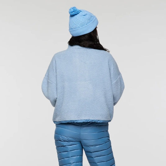 Person wearing a blue knit outfit with a matching beanie on a light gray background