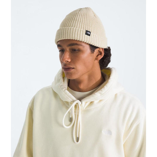Person wearing a cream beanie and hoodie on a white background