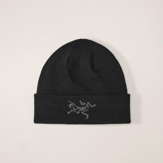 Black beanie with a white logo on a beige background