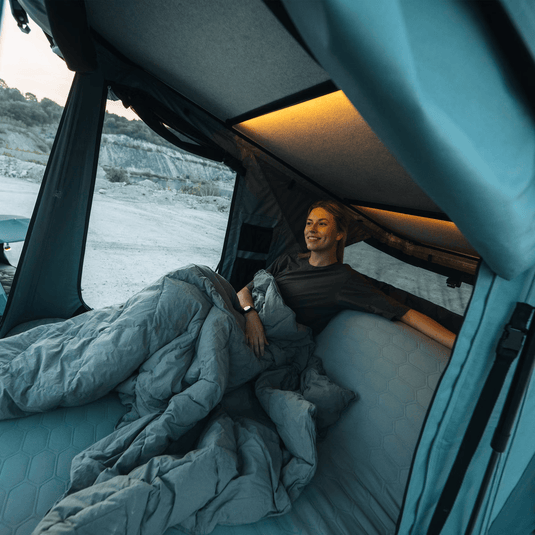 Person lying in a van bed with a scenic view outside