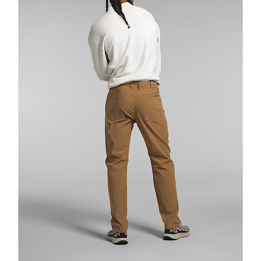 Person wearing a white sweater and brown pants on a gray background