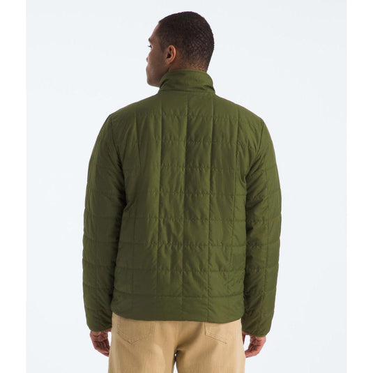 Person wearing a green quilted jacket on a white background