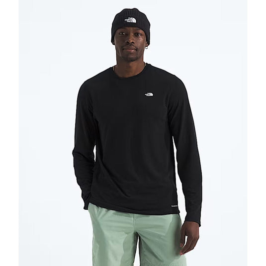 Man wearing a black long-sleeve shirt and light green pants on a white background