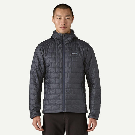 Man wearing a gray quilted jacket with a brand logo on a white background