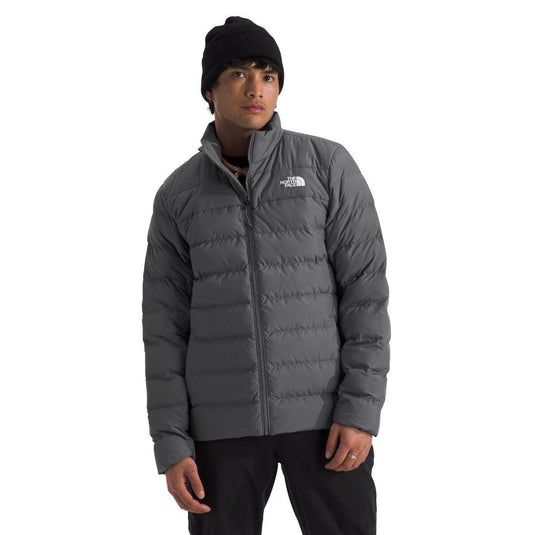 Person wearing a gray puffer jacket with a brand logo on a white background