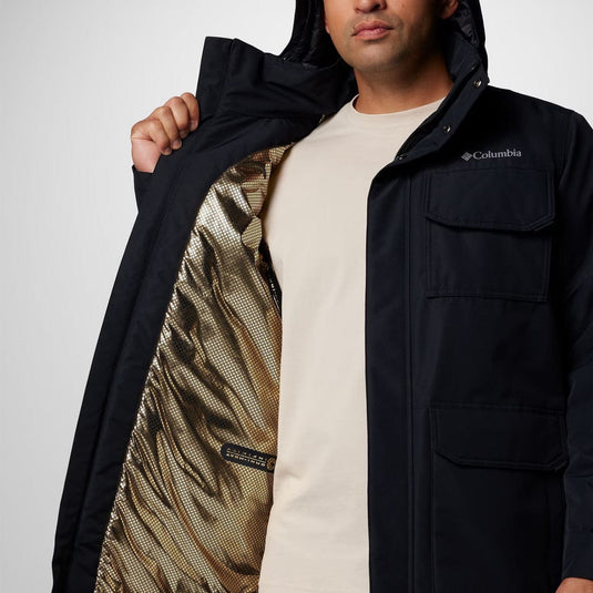 Person wearing a black Columbia jacket with a white shirt underneath, on a plain background