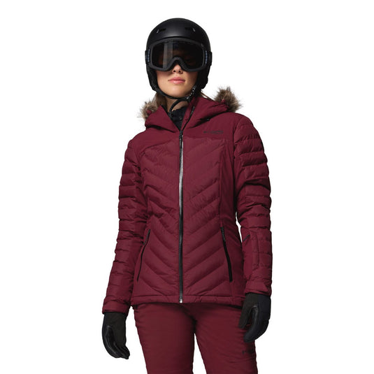 Person wearing a maroon winter jacket, helmet, and goggles on a white background