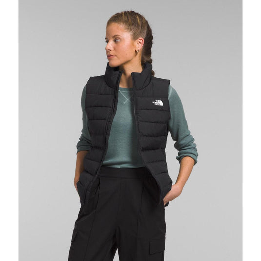Person wearing a black puffer vest with a logo on a gray background
