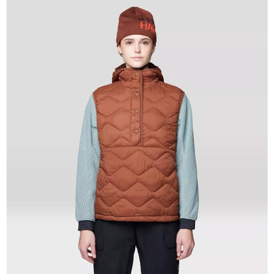 Person wearing a brown quilted vest and beanie on a light gray background
