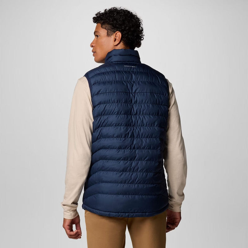 Load image into Gallery viewer, Person wearing a navy puffer vest over a beige shirt on a white background
