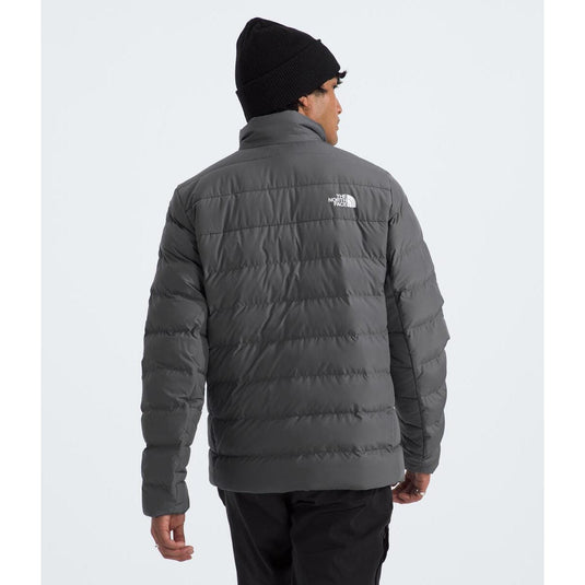 Person wearing a gray puffer jacket with a brand logo on a white background