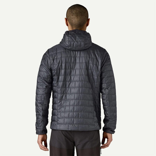 Person wearing a dark gray quilted jacket on a white background
