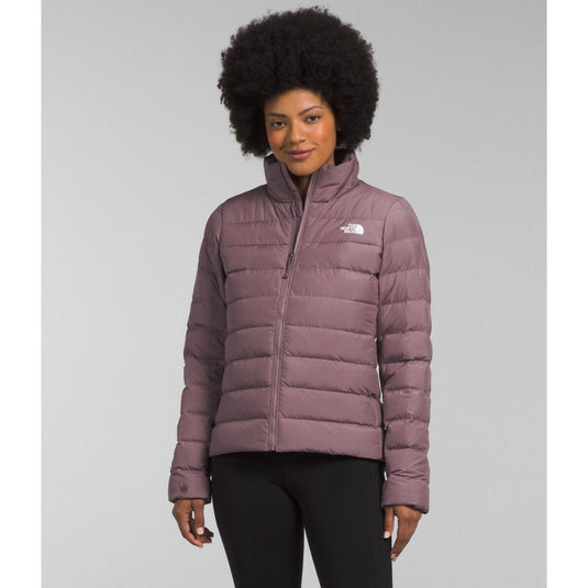 Woman wearing a purple puffer jacket with a brand logo on a gray background
