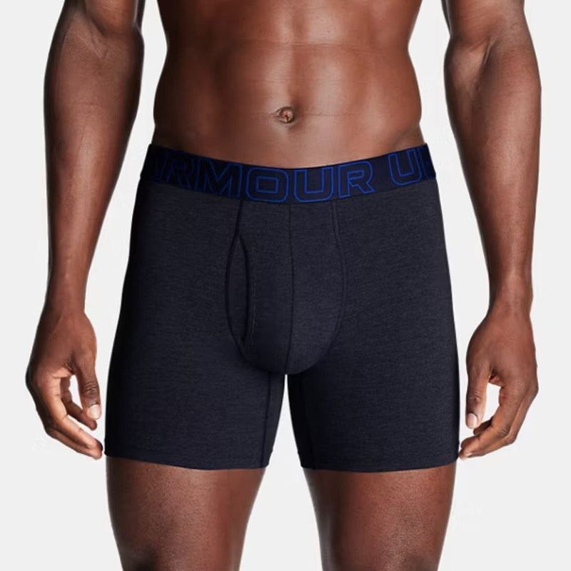 Load image into Gallery viewer, Man wearing navy boxer briefs with blue waistband on a light gray background
