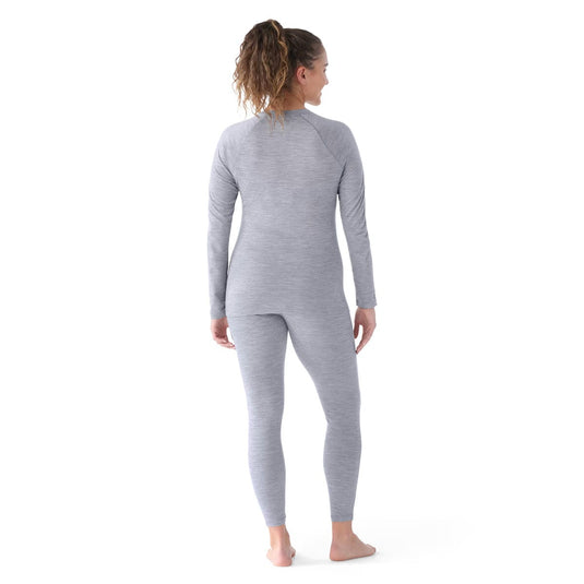 Woman wearing a gray long-sleeve top and leggings set on a white background
