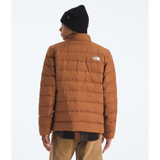 Person wearing a brown puffer jacket with a visible brand logo on a white background