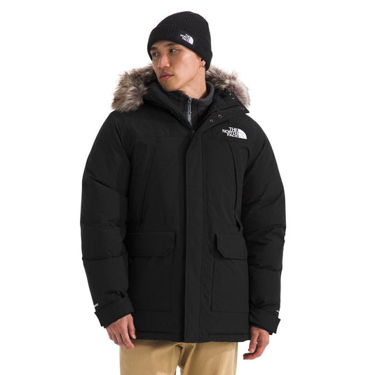 Person wearing a black coat with fur hood and matching hat on a white background