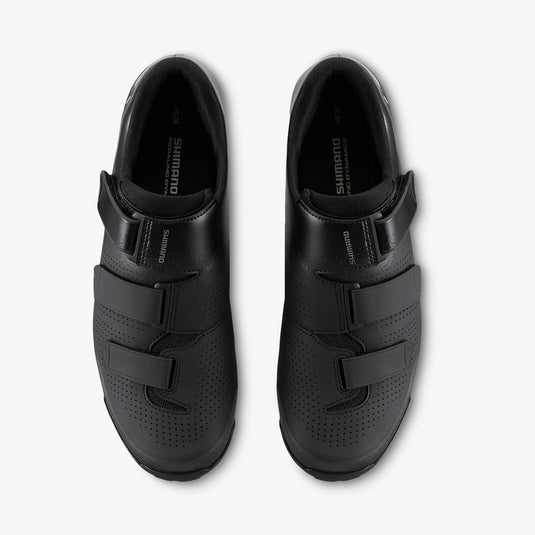 Pair of black cycling shoes with velcro straps on a white background