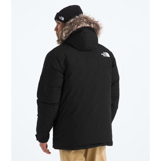 Person wearing a black jacket with fur hood on a white background