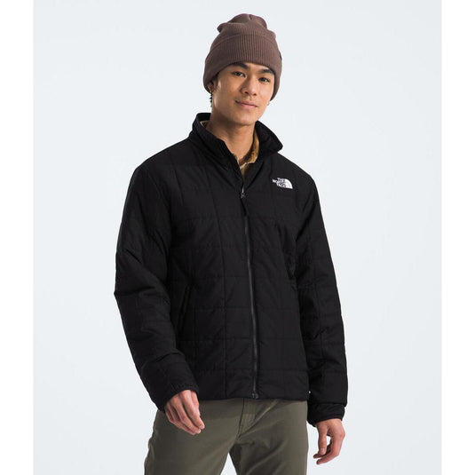 Person wearing a black jacket with a brand logo on a white background